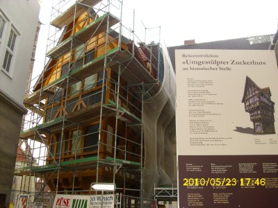 Farbfoto: Der Nachbau von dem Fachwerkhaus Umgestülpter Zuckerhut in Hildesheim am Pfingstsonntag des Jahres 2010. Links vom Umgestülpten Zuckerhut im Bildhintergrund die Andreaskirche. Fotograf: Kim Hartley.